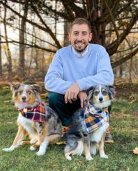 Nicolas Angione posing with his two Australian Shepherds